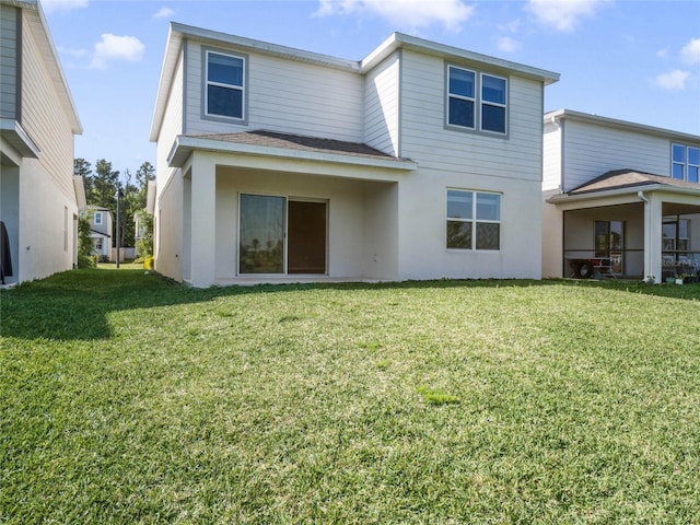 rear view of property featuring a lawn and stucco siding