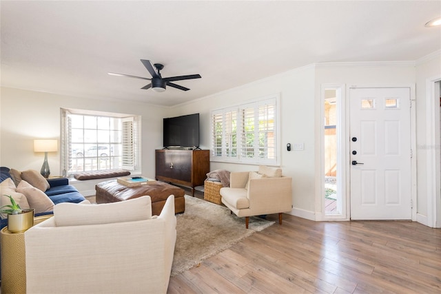 living area with crown molding, a ceiling fan, light wood-type flooring, and a wealth of natural light