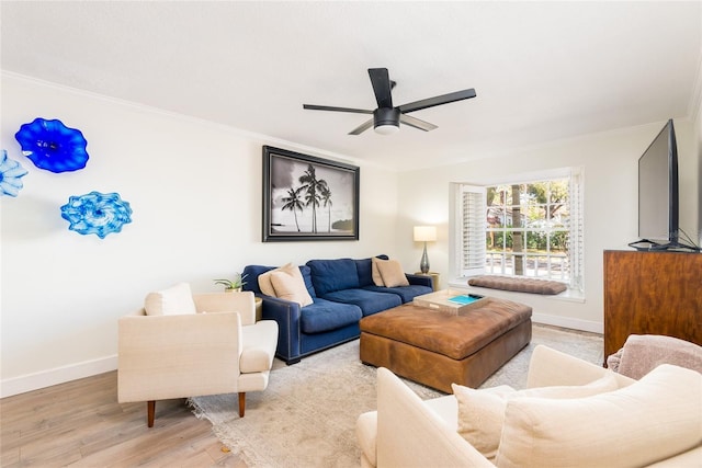 living area featuring ornamental molding, baseboards, light wood-type flooring, and ceiling fan