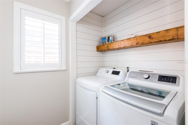 laundry room with laundry area, wooden walls, and washing machine and clothes dryer