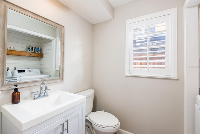 half bath with washer / clothes dryer, toilet, and vanity