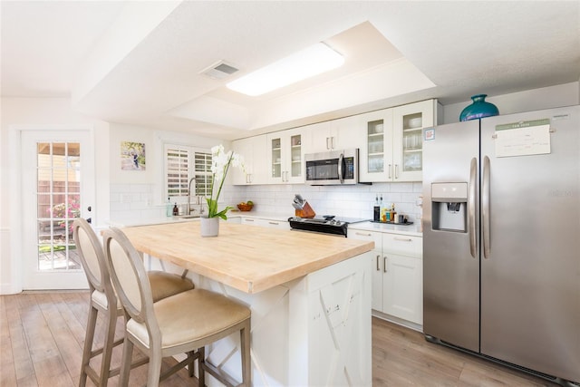 kitchen with visible vents, a raised ceiling, appliances with stainless steel finishes, and a breakfast bar area