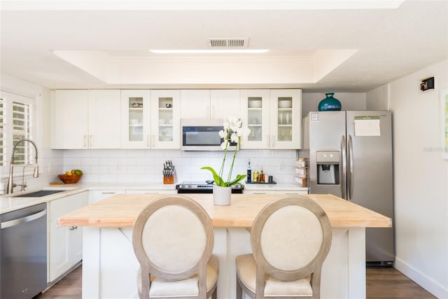 kitchen featuring visible vents, a tray ceiling, a sink, butcher block countertops, and appliances with stainless steel finishes