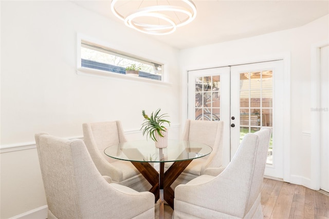 dining space featuring a notable chandelier, light wood-style floors, baseboards, and french doors