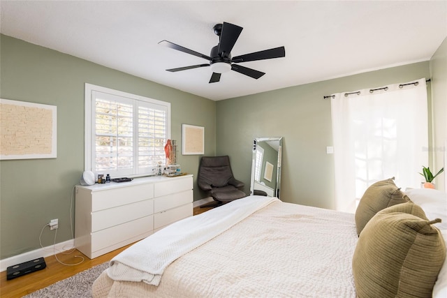 bedroom with baseboards, light wood finished floors, and ceiling fan