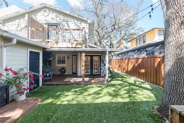 rear view of property with a balcony, a yard, and fence