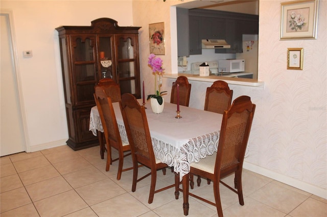 dining room with light tile patterned flooring, wallpapered walls, and baseboards