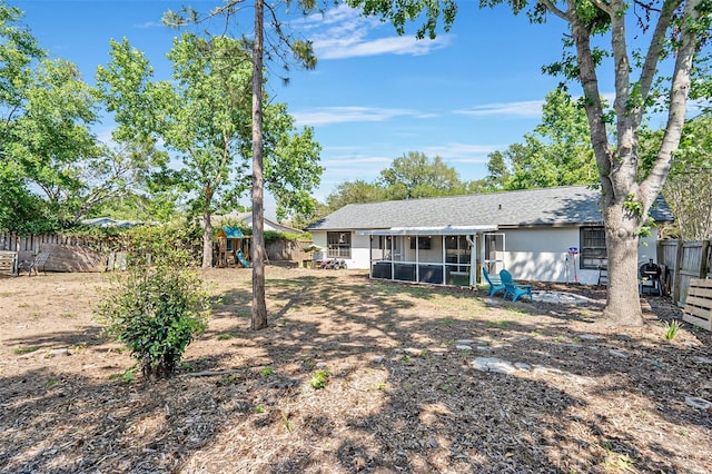 back of property featuring a fenced backyard, a playground, a sunroom, and roof with shingles
