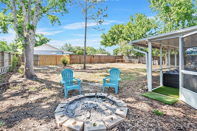 view of yard featuring a fenced backyard, a fire pit, and a sunroom