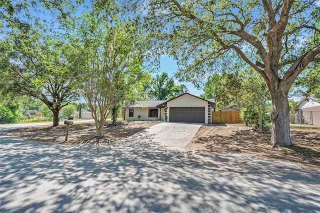 ranch-style house featuring an attached garage, fence, and driveway