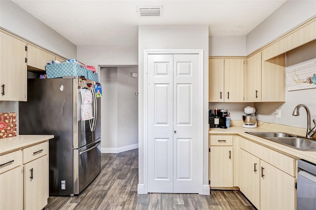 kitchen with a sink, light countertops, appliances with stainless steel finishes, and light brown cabinetry
