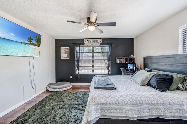 bedroom with ceiling fan, multiple windows, baseboards, and wood finished floors