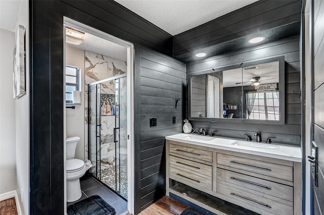 bathroom with toilet, a stall shower, double vanity, and a sink