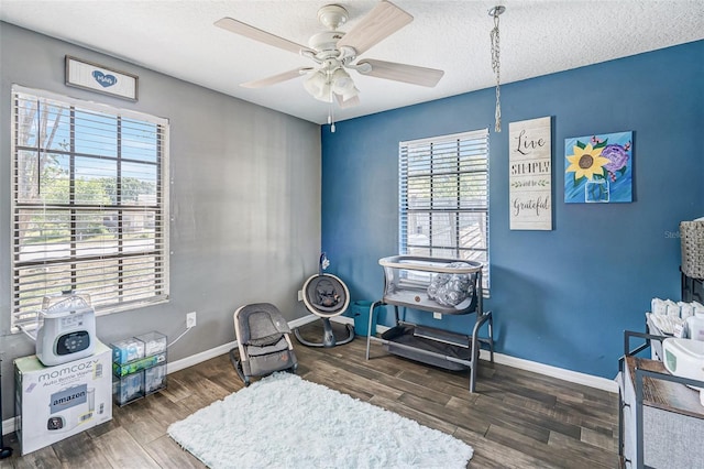 sitting room with a textured ceiling, wood finished floors, ceiling fan, and baseboards