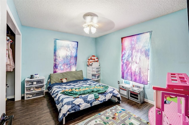 bedroom with a textured ceiling, wood finished floors, and baseboards