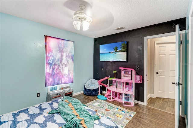 bedroom with visible vents, baseboards, ceiling fan, a textured ceiling, and wood finished floors