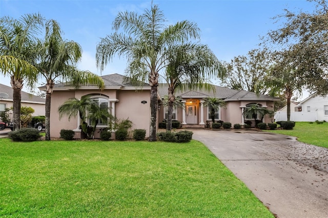 mediterranean / spanish house featuring stucco siding, driveway, and a front yard