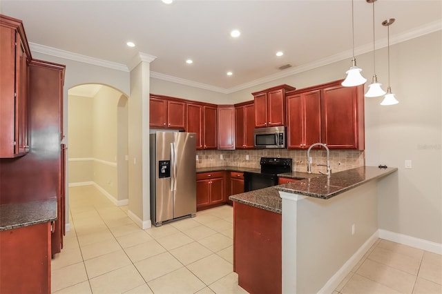 kitchen featuring a peninsula, arched walkways, stainless steel appliances, dark brown cabinets, and tasteful backsplash