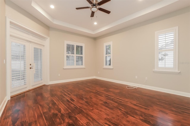 unfurnished room featuring baseboards, a tray ceiling, recessed lighting, dark wood-type flooring, and french doors