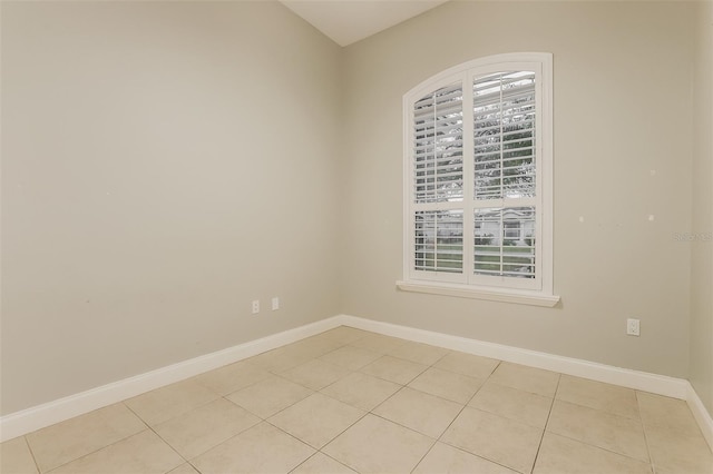 spare room featuring light tile patterned floors, baseboards, and plenty of natural light