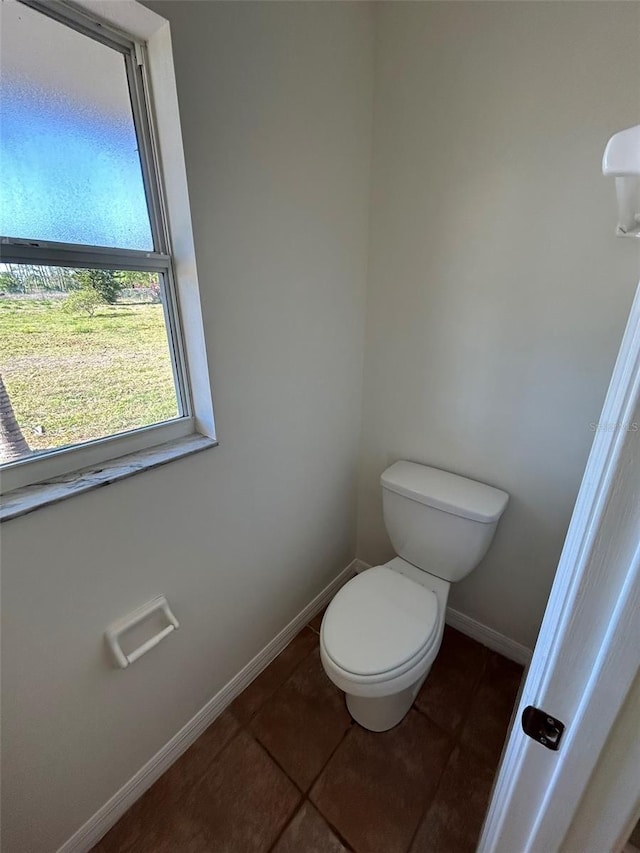 bathroom with baseboards, toilet, and tile patterned flooring