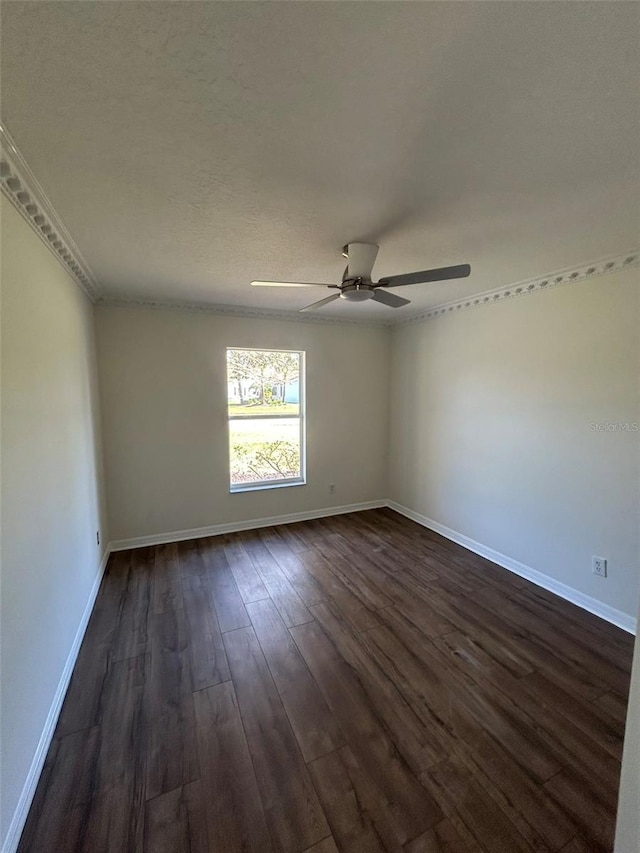 spare room featuring baseboards, dark wood finished floors, and a ceiling fan