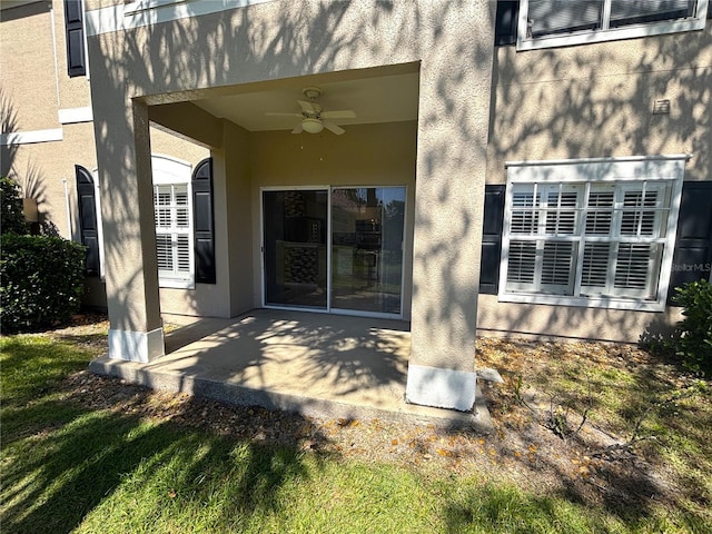 entrance to property featuring stucco siding, a patio, and a ceiling fan