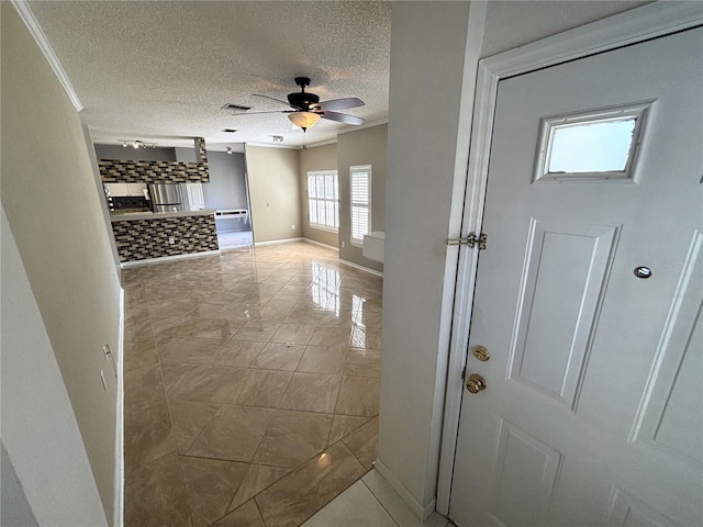 hall featuring visible vents, a textured ceiling, crown molding, and baseboards