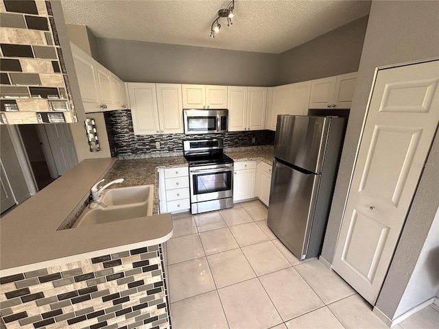 kitchen featuring light tile patterned floors, decorative backsplash, stainless steel appliances, and a sink