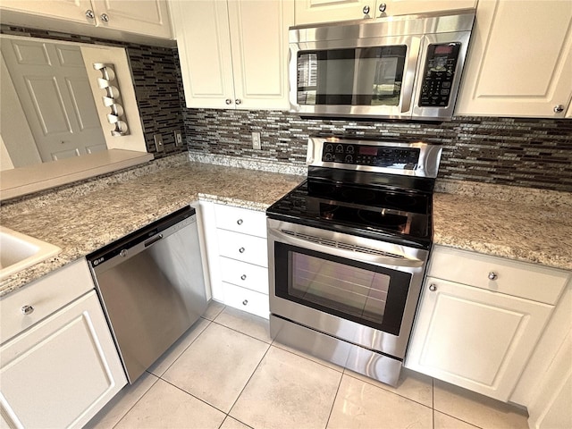 kitchen with light tile patterned flooring, backsplash, stainless steel appliances, and light stone countertops