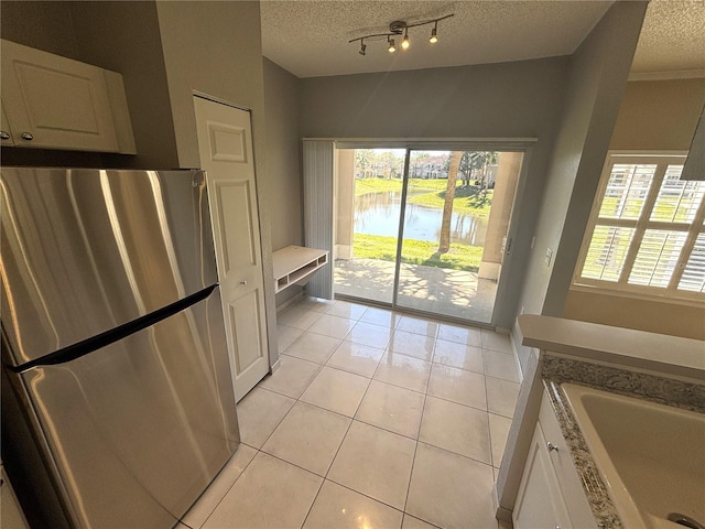 kitchen with light tile patterned floors, plenty of natural light, a textured ceiling, and freestanding refrigerator