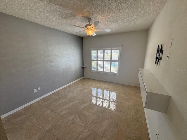 spare room with a textured ceiling, baseboards, and ceiling fan