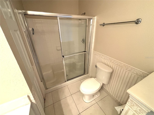 bathroom featuring vanity, tile patterned flooring, a shower stall, wainscoting, and toilet