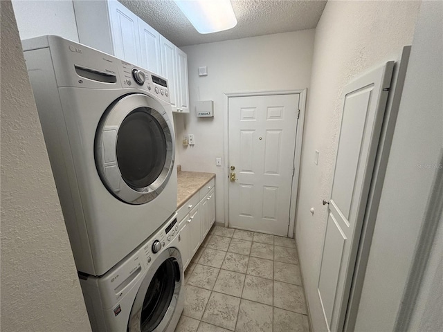 clothes washing area with cabinet space, stacked washer and clothes dryer, and a textured ceiling