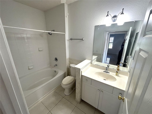 full bathroom featuring toilet, tile patterned flooring, tub / shower combination, vanity, and a textured wall