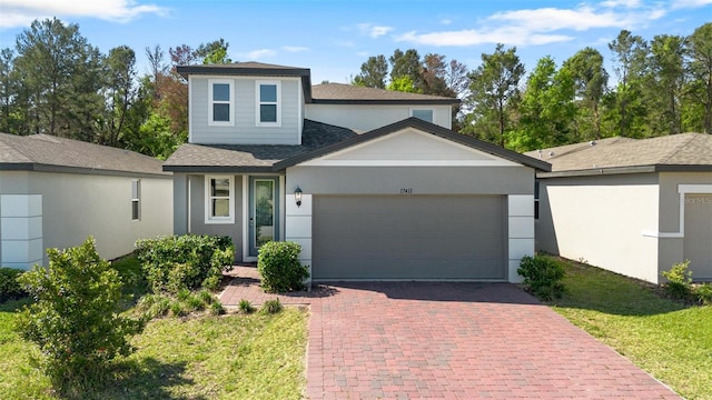 traditional home with stucco siding, decorative driveway, a garage, and roof with shingles