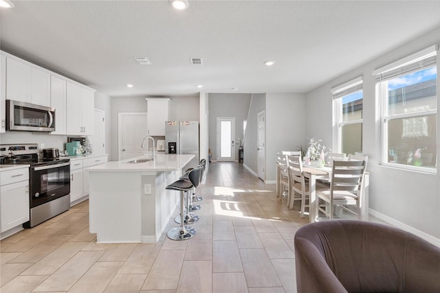 kitchen with a sink, stainless steel appliances, a wealth of natural light, and visible vents