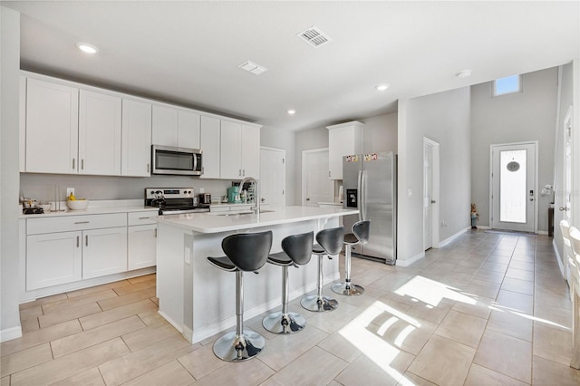 kitchen with light countertops, a breakfast bar area, a sink, visible vents, and appliances with stainless steel finishes