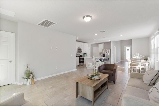 living area with baseboards, visible vents, and recessed lighting