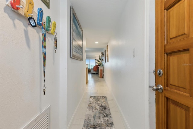 corridor featuring light tile patterned flooring and baseboards