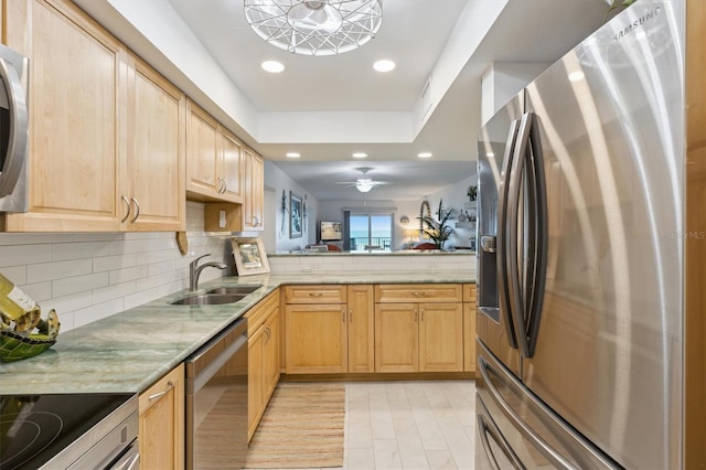 kitchen with a sink, tasteful backsplash, appliances with stainless steel finishes, and light brown cabinets