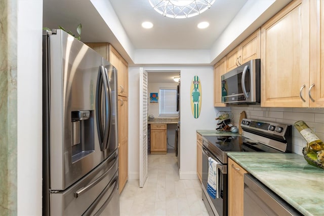 kitchen featuring baseboards, light brown cabinetry, light countertops, decorative backsplash, and appliances with stainless steel finishes