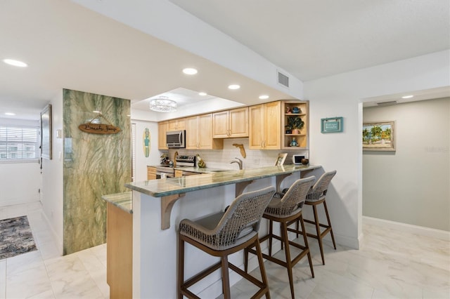 kitchen featuring light brown cabinetry, marble finish floor, appliances with stainless steel finishes, and tasteful backsplash