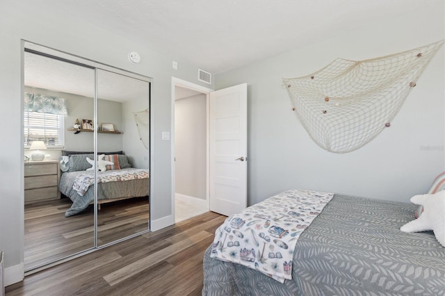 bedroom featuring a closet, visible vents, baseboards, and wood finished floors