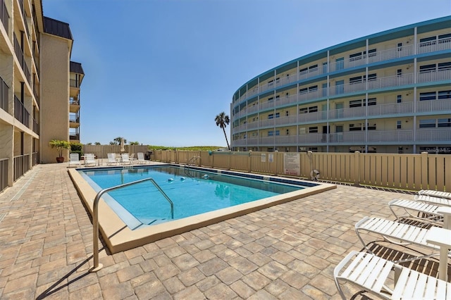 pool with a patio area and fence