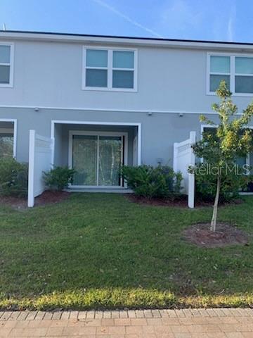 rear view of property with stucco siding and a yard