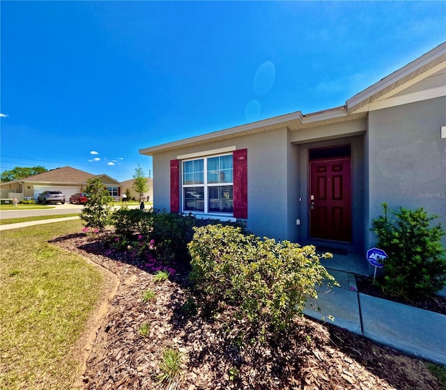 entrance to property featuring stucco siding and a lawn