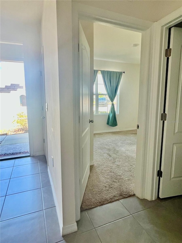 corridor with tile patterned flooring, carpet flooring, and baseboards