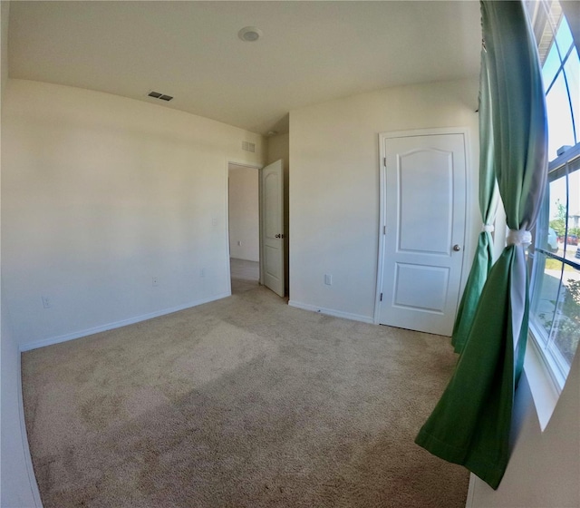 carpeted empty room featuring baseboards and visible vents