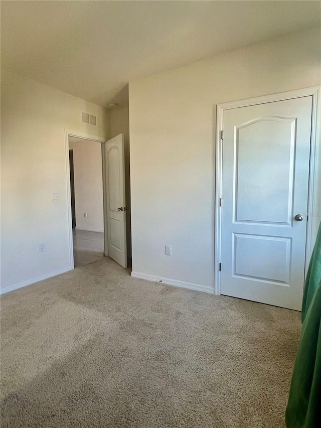 unfurnished bedroom with light colored carpet, visible vents, and baseboards